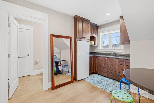 kitchen featuring white refrigerator, sink, dark brown cabinets, and light hardwood / wood-style flooring