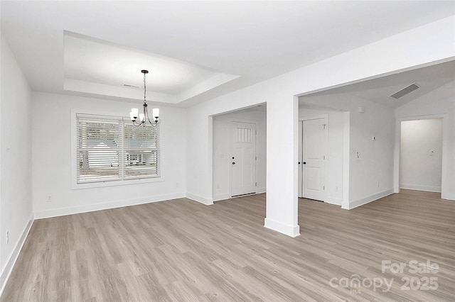 unfurnished dining area featuring a chandelier, a raised ceiling, and light hardwood / wood-style floors