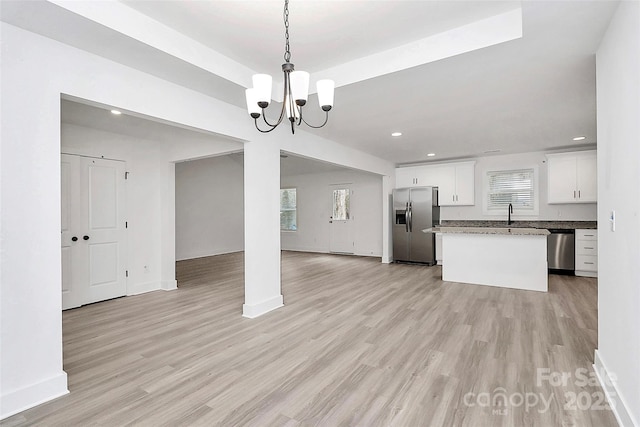 kitchen featuring appliances with stainless steel finishes, a kitchen island, pendant lighting, light hardwood / wood-style floors, and white cabinets