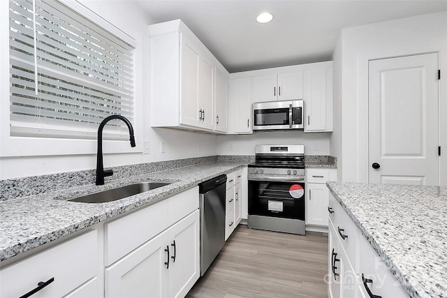 kitchen featuring light stone counters, stainless steel appliances, and white cabinets