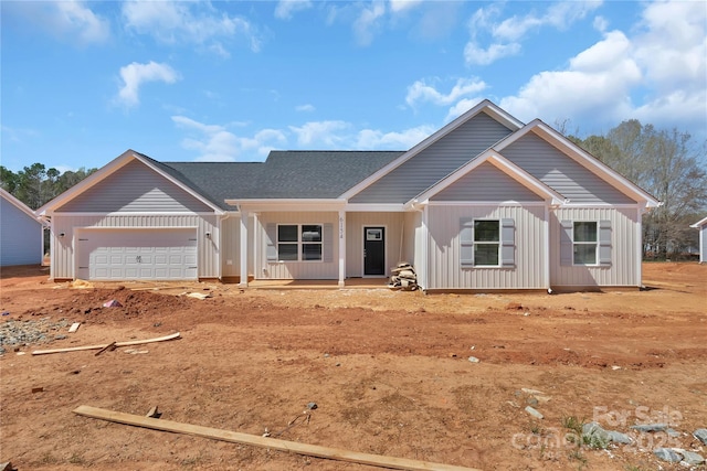 view of front of house with an attached garage, a porch, board and batten siding, and roof with shingles