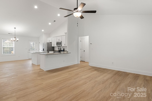 kitchen with white cabinetry, light wood-type flooring, light stone countertops, and appliances with stainless steel finishes