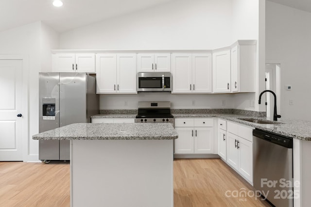 kitchen with stainless steel appliances, white cabinetry, light stone countertops, and sink