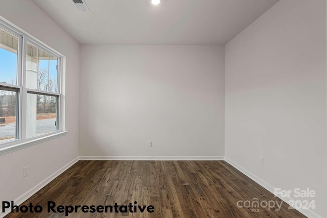 empty room with a wealth of natural light and dark hardwood / wood-style floors