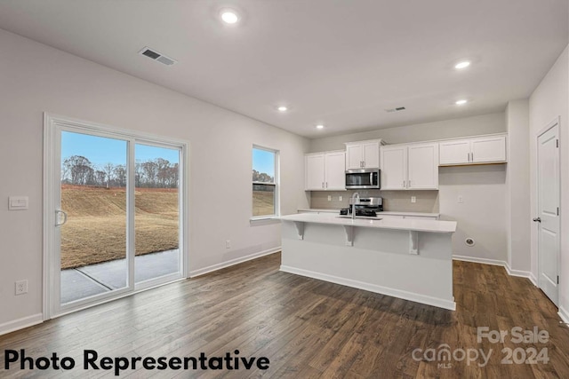 kitchen with dark hardwood / wood-style floors, stainless steel appliances, backsplash, a center island with sink, and white cabinets