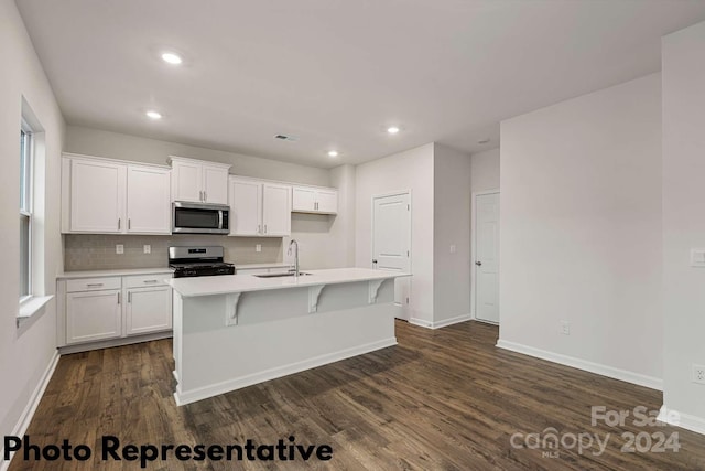 kitchen featuring dark hardwood / wood-style floors, stainless steel appliances, a kitchen island with sink, and white cabinetry