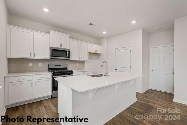 kitchen with an island with sink, sink, dark wood-type flooring, and appliances with stainless steel finishes