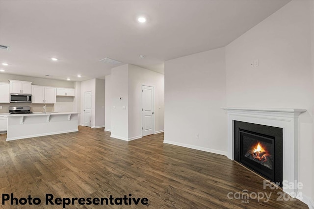 unfurnished living room featuring sink and hardwood / wood-style flooring