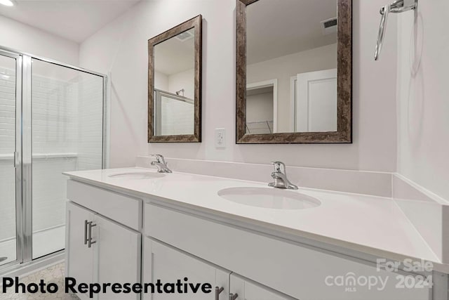 bathroom featuring an enclosed shower, dual sinks, and vanity with extensive cabinet space