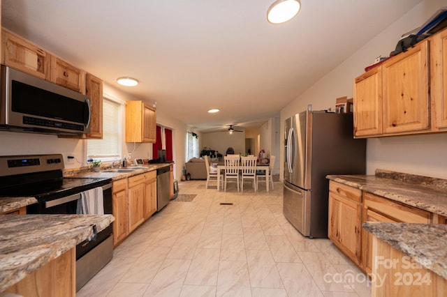 kitchen with ceiling fan, sink, stainless steel appliances, and dark stone countertops