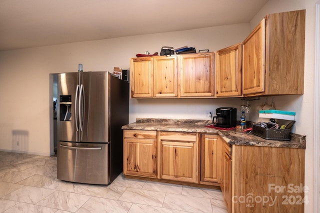 kitchen featuring stainless steel refrigerator with ice dispenser and dark stone counters