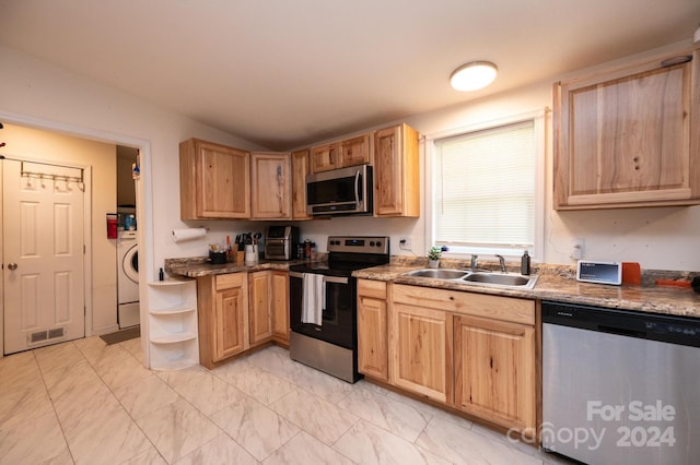 kitchen featuring washer / dryer, stainless steel appliances, light brown cabinets, vaulted ceiling, and sink