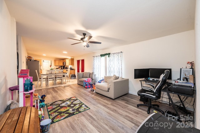 living room with ceiling fan, vaulted ceiling, and light hardwood / wood-style flooring