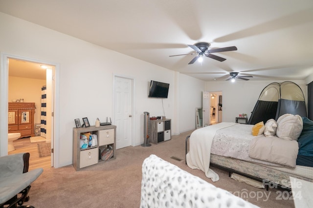 bedroom with ceiling fan, light carpet, and ensuite bathroom