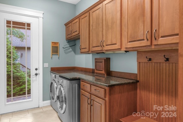 clothes washing area with cabinets, plenty of natural light, light tile floors, and washing machine and clothes dryer