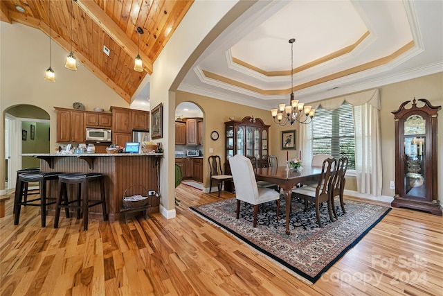 dining area featuring a raised ceiling, an inviting chandelier, and light wood-type flooring