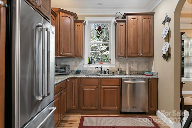 kitchen featuring appliances with stainless steel finishes, sink, light hardwood / wood-style flooring, and tasteful backsplash