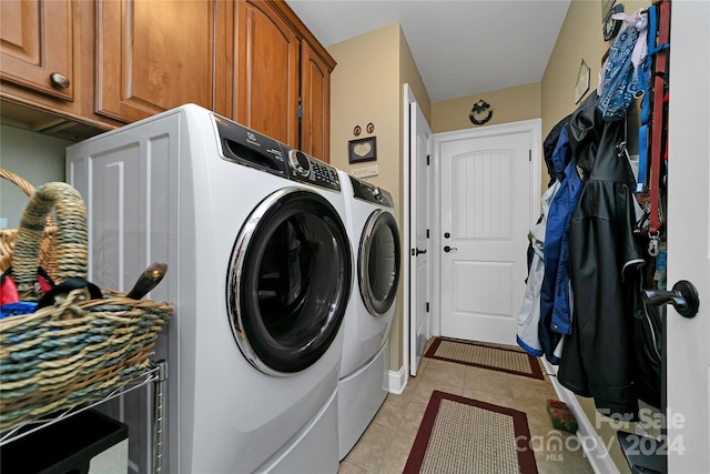 laundry area with washing machine and clothes dryer, cabinets, and light tile floors