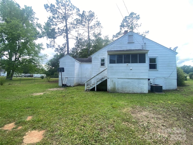 back of house with central air condition unit and a lawn