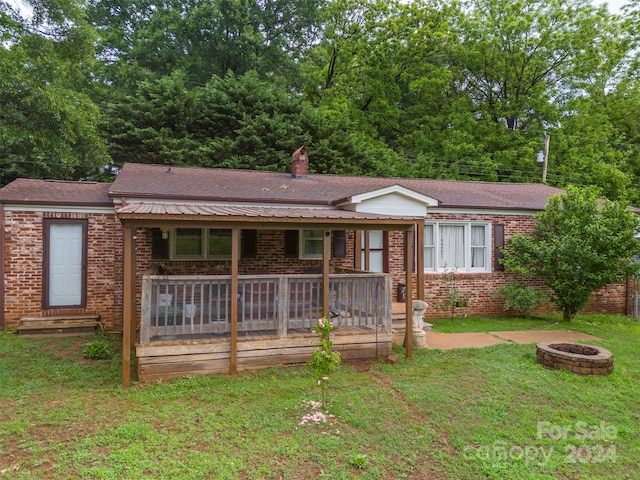 view of front of property with a front yard, an outdoor fire pit, and a wooden deck