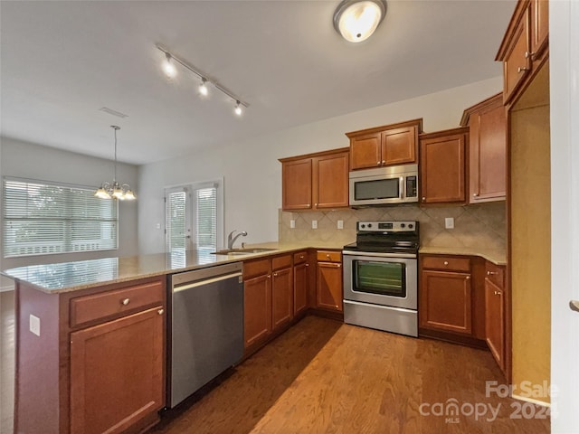 kitchen featuring decorative light fixtures, kitchen peninsula, a notable chandelier, dark wood-type flooring, and appliances with stainless steel finishes