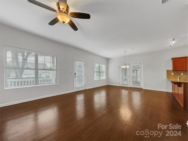 unfurnished living room featuring sink, dark hardwood / wood-style floors, and ceiling fan with notable chandelier