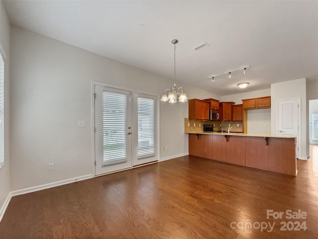 unfurnished living room with wood-type flooring, sink, an inviting chandelier, and track lighting