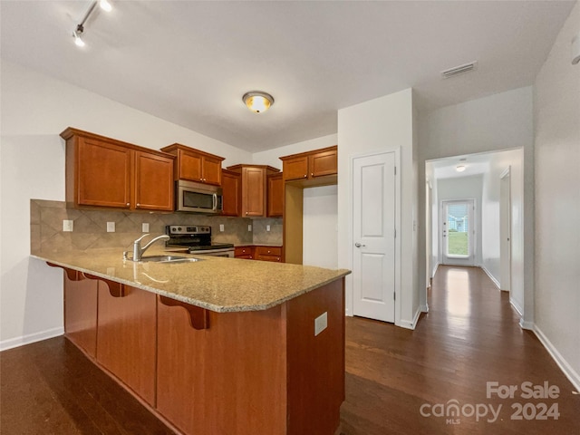 kitchen featuring stainless steel appliances, tasteful backsplash, rail lighting, dark wood-type flooring, and sink