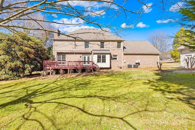 rear view of property featuring brick siding, a lawn, and a wooden deck