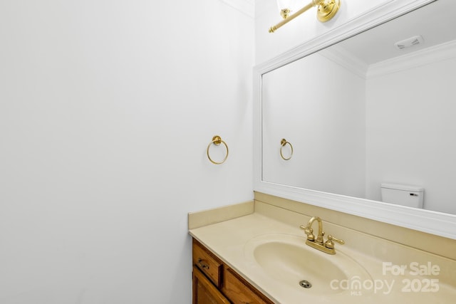 bathroom with visible vents, toilet, vanity, and crown molding