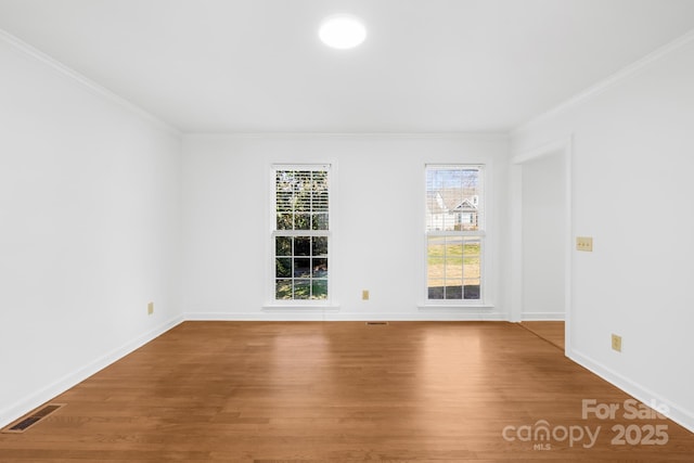 empty room with baseboards, crown molding, visible vents, and wood finished floors