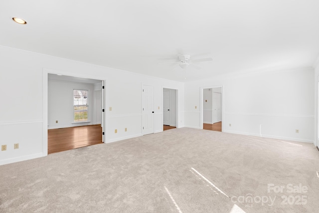 carpeted spare room featuring ceiling fan and baseboards