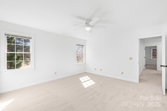 empty room with baseboards, a ceiling fan, and light colored carpet