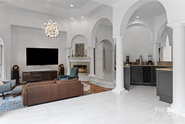 living room featuring a high ceiling, ornamental molding, a notable chandelier, and a premium fireplace