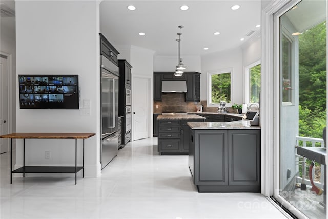 kitchen featuring light stone counters, backsplash, crown molding, pendant lighting, and stainless steel built in fridge