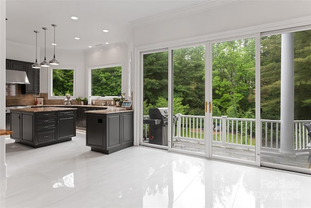 kitchen with tasteful backsplash, ornamental molding, pendant lighting, gray cabinets, and a kitchen island