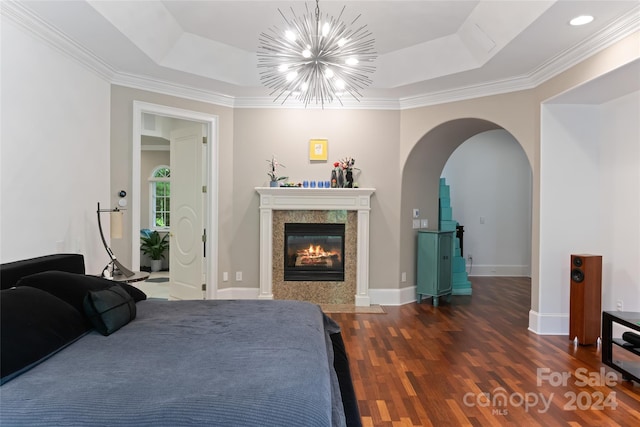 bedroom featuring a chandelier, a tray ceiling, crown molding, and dark wood-type flooring