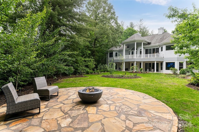 rear view of property with a yard, a patio area, a balcony, and an outdoor fire pit