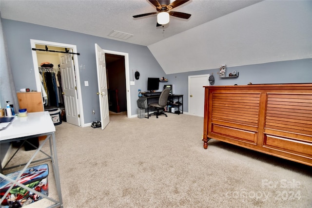 carpeted bedroom with a walk in closet, a textured ceiling, lofted ceiling, a closet, and ceiling fan