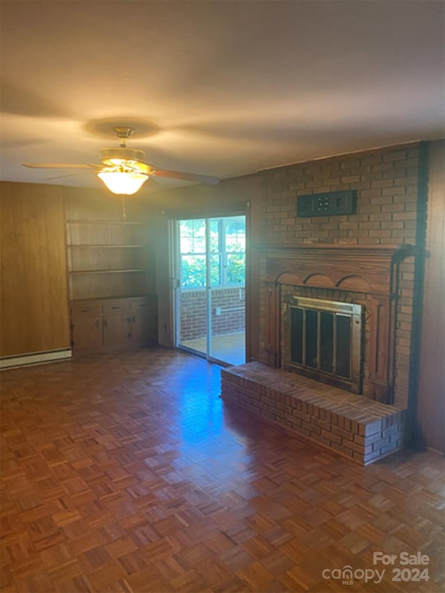 unfurnished living room featuring a baseboard heating unit, dark parquet floors, a brick fireplace, and ceiling fan