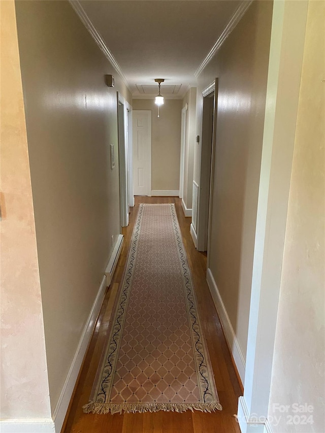 corridor featuring crown molding, a baseboard heating unit, and hardwood / wood-style floors