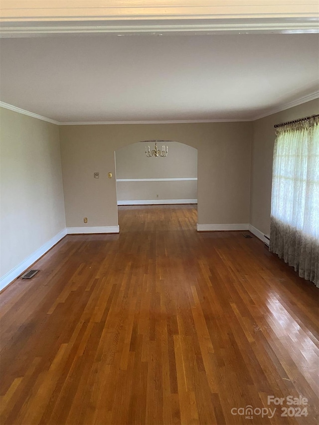 empty room with ornamental molding and wood-type flooring