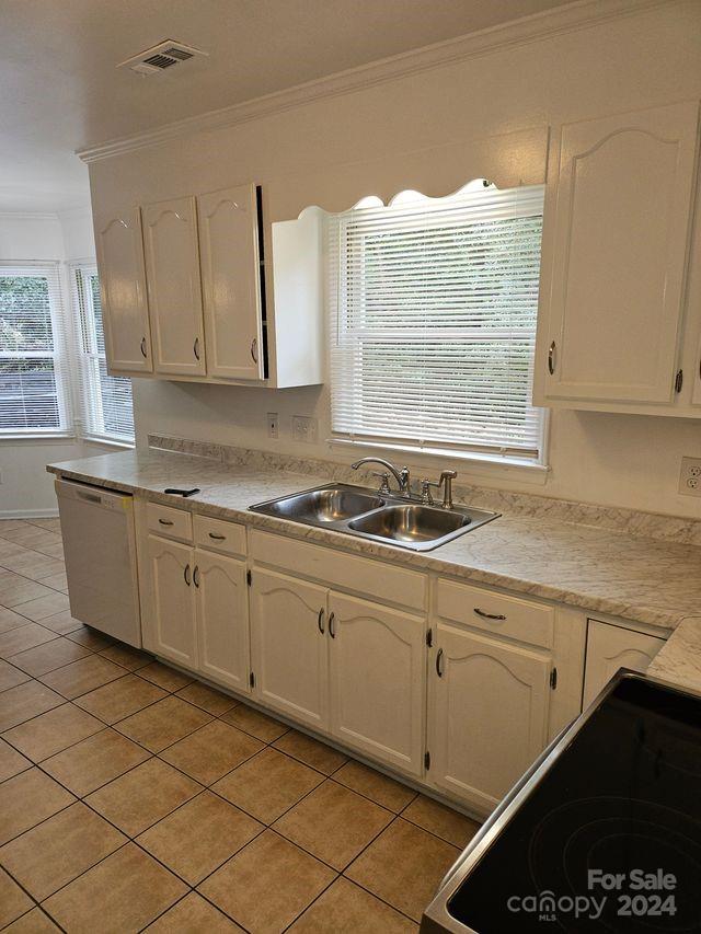 kitchen featuring plenty of natural light, sink, dishwashing machine, and light tile floors