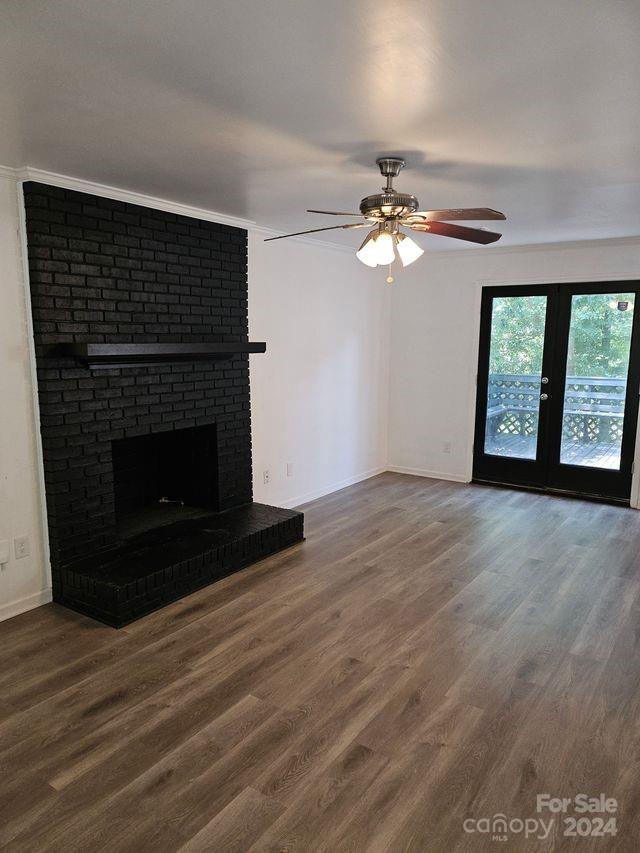 unfurnished living room with dark hardwood / wood-style floors, ceiling fan, a fireplace, and crown molding