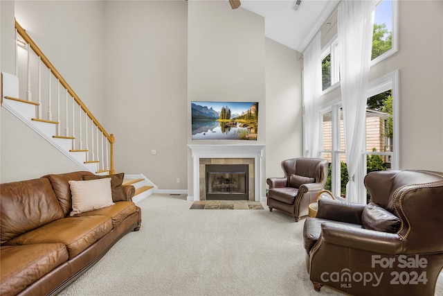 carpeted living room featuring a tiled fireplace and high vaulted ceiling