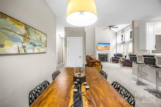 carpeted dining room featuring a tiled fireplace and ceiling fan