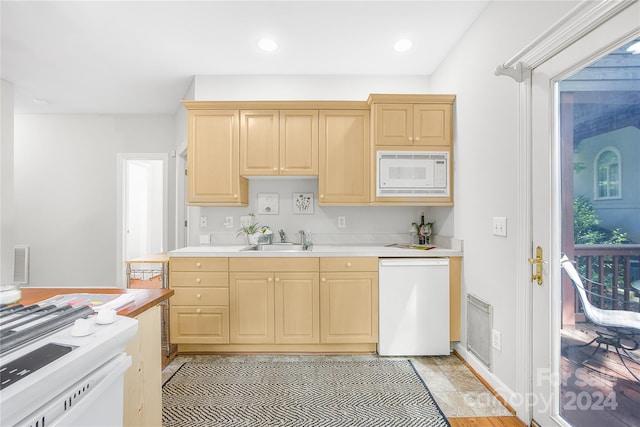 kitchen with white appliances, a healthy amount of sunlight, light brown cabinetry, and sink