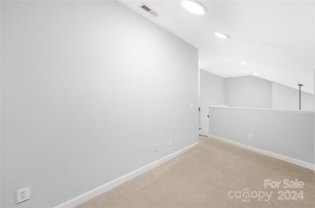 carpeted spare room featuring lofted ceiling