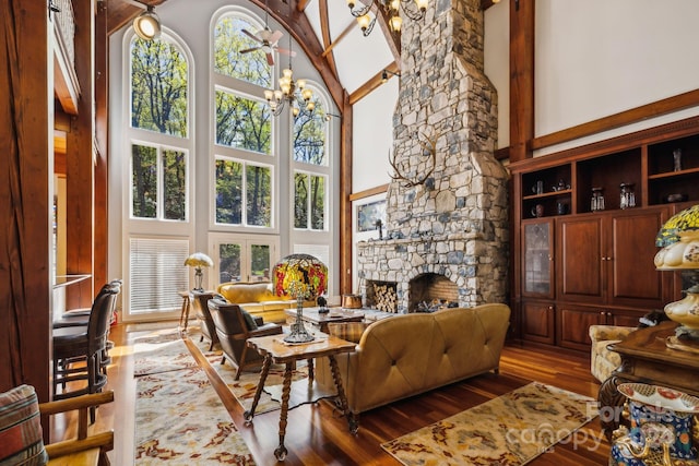 living room with a fireplace, beamed ceiling, hardwood / wood-style flooring, high vaulted ceiling, and a notable chandelier