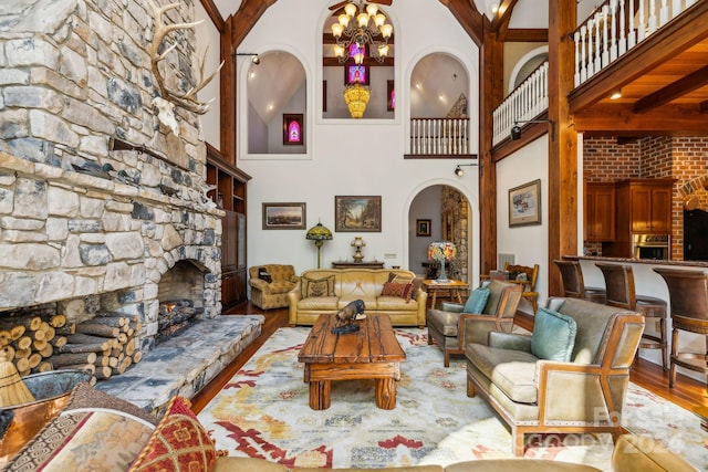 living room featuring a chandelier, a fireplace, hardwood / wood-style flooring, beam ceiling, and a high ceiling